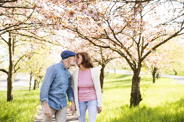 a man and woman kissing on a path under flowering trees