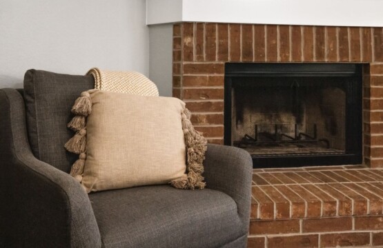 A comfortable couch with a pillow and a blanket in front of a fireplace