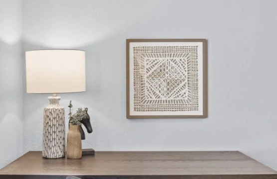 A workspace in the corner of the bedroom includes a desk, a lamp, a picture on the wall, and a cushy gray velvet office chair.