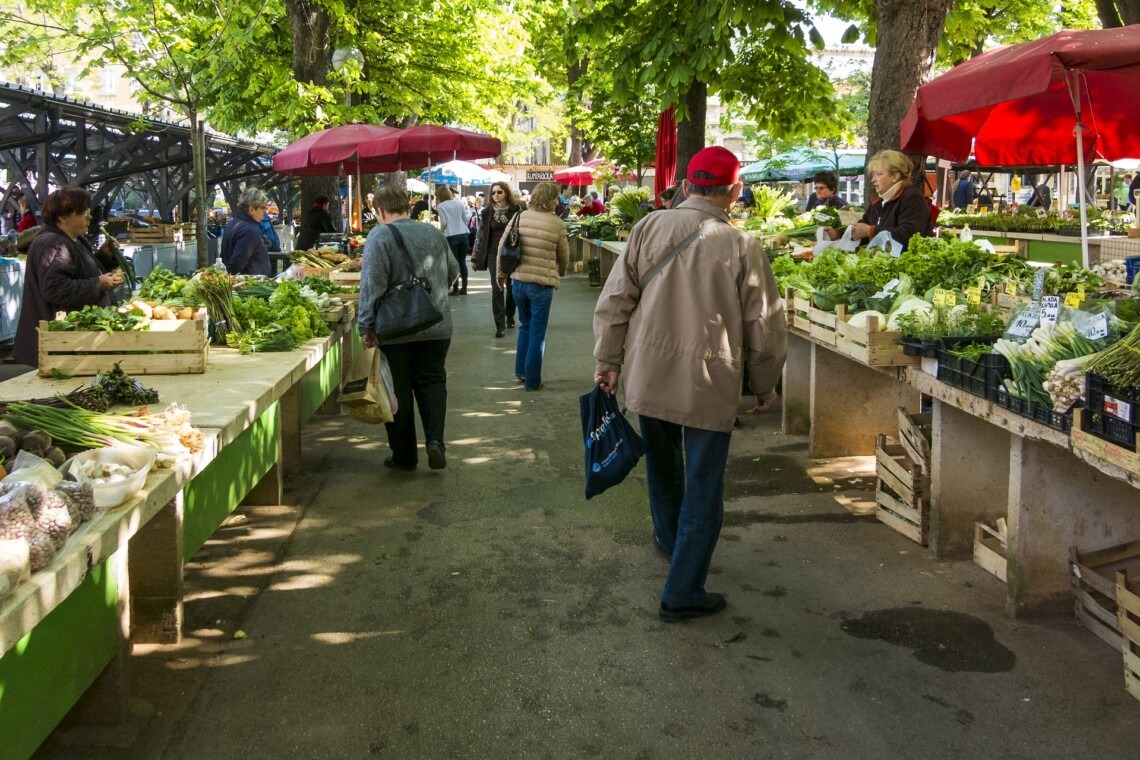 people walking on a street with many produce on display