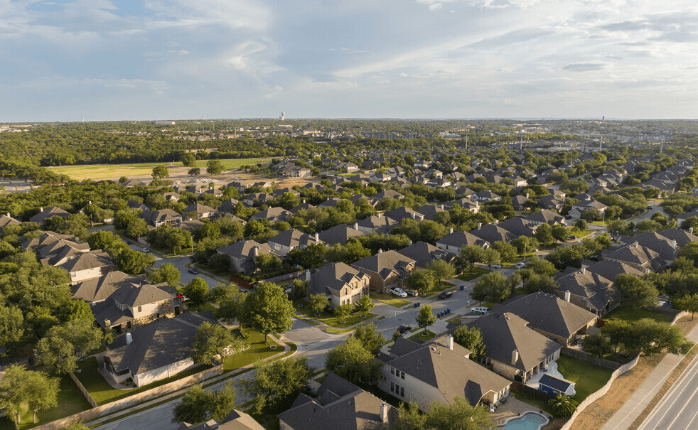 Bird’s-eye view of a picturesque neighborhood in Cedar Park, Texas, featuring tree-lined streets, beautiful homes, and a tranquil suburban setting.