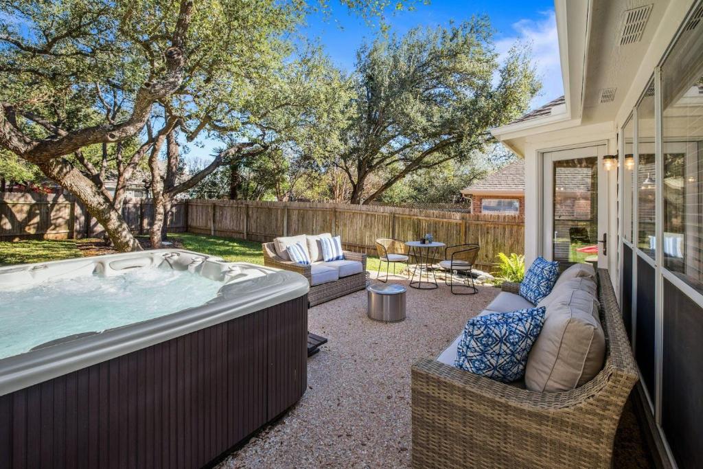 Backyard of Autumn Fire BnB in Cedar Park, Texas, featuring a hot tub, spacious lawns, and mature trees, offering a peaceful and relaxing outdoor space.