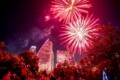 Fireworks display lighting up the night sky during the Cedar Park 4th of July Celebration, with vibrant red and pink bursts over a festive crowd gathered between Cedar Park and Austin, Texas.