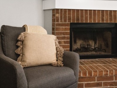 A comfortable couch with a pillow and a blanket in front of a fireplace