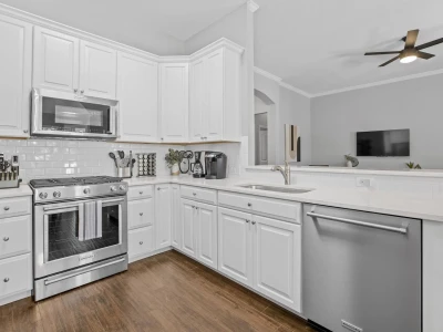 A fully functional kitchen featuring white cabinets and stainless steel appliances, including a full oven with a gas range.