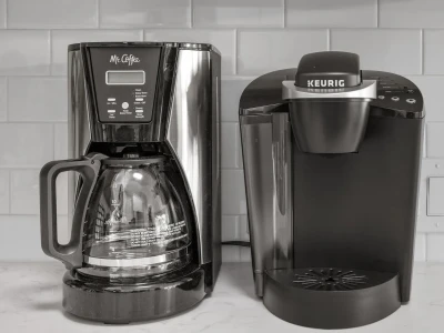 A pair of stylish black coffee makers, set against clean and glossy kitchen tiles in the backdrop.