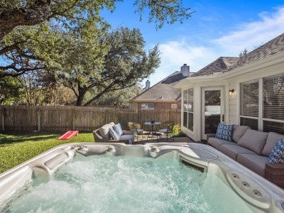 A hot tub offers a serene view of the trees and a charming wooden fence in the backyard.