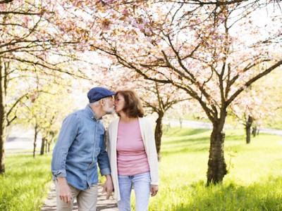 a man and woman kissing on a path under flowering trees